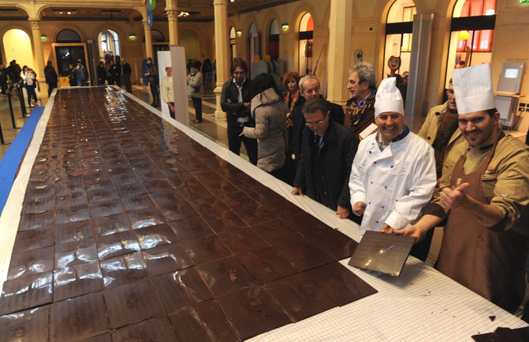 'GWR Day 2011 in Italy with an impressive 15 meters long delicious chocolate bar! 
Mirco Della Vecchia (Italy) an internationally recognised chocolate master and already record holder for the largest chocolate sculpture and the tallest ice cream has set a new record by making a 15.09 m long and 2.03 m wide chocolate bar. Della Vecchia' record breaking team was formed in this occasion by Mirco Della Vecchia, Renato Zoia and Giuseppe Sartori (all Italy) for an event organised by BF Servizi Gruppo BolognaFiere during the 7th edition of the Cioccoshow fair, in Bologna.
The chocolate bar was officially measured by GWR Lucia Sinigagliesi inside the historic Salaborsa library in Bologna main 'Maggiore Square'.